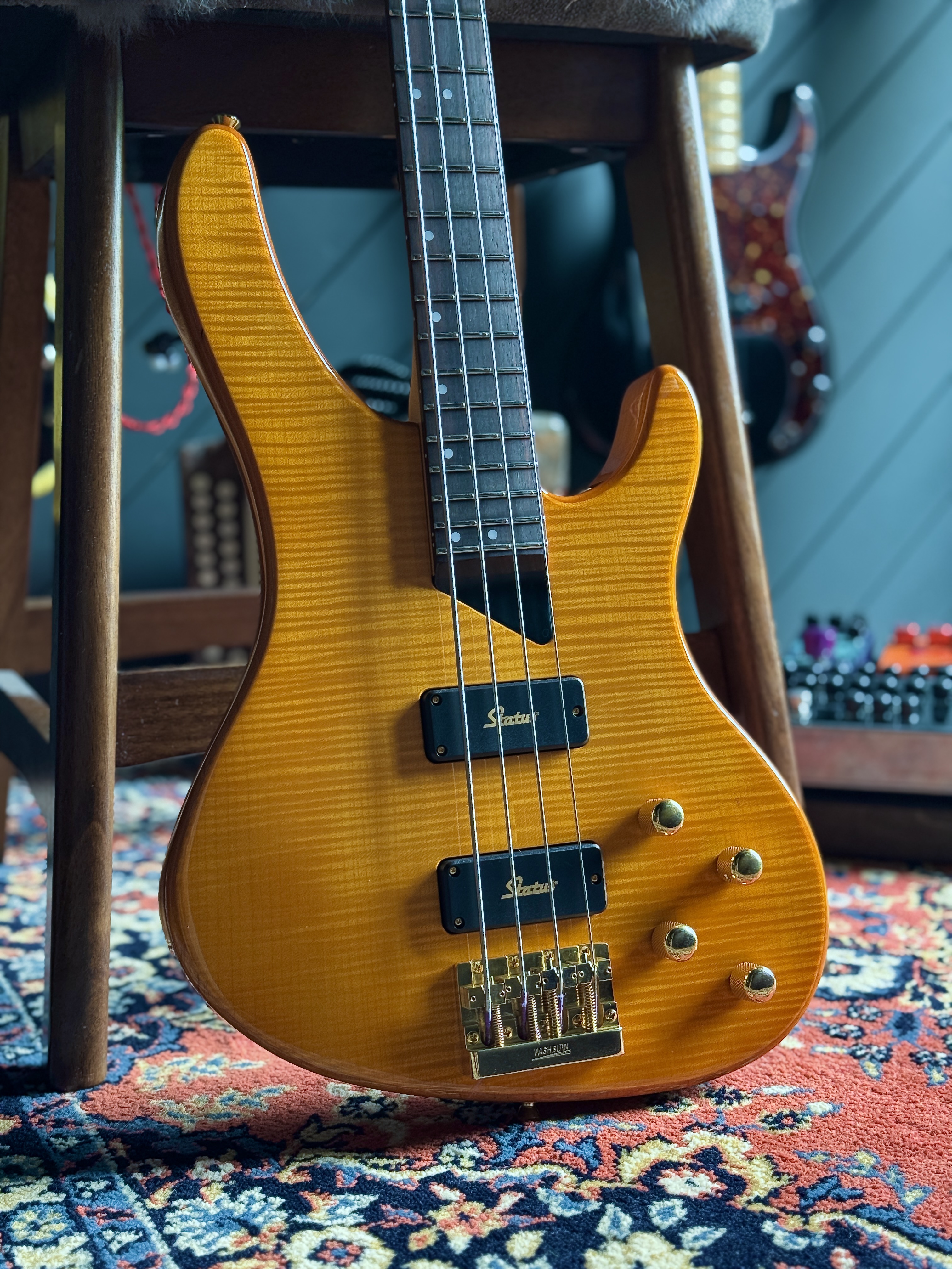 Front close-up showing the flame-maple top, Status pickups and gold bridge